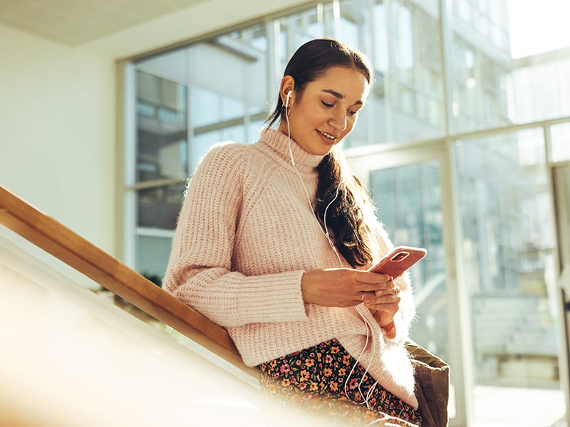 Student looks at phone while walking down stairs